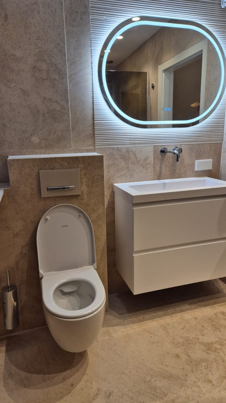 Badkamer in beige marmer met zwevend meubel en verlichte spiegel