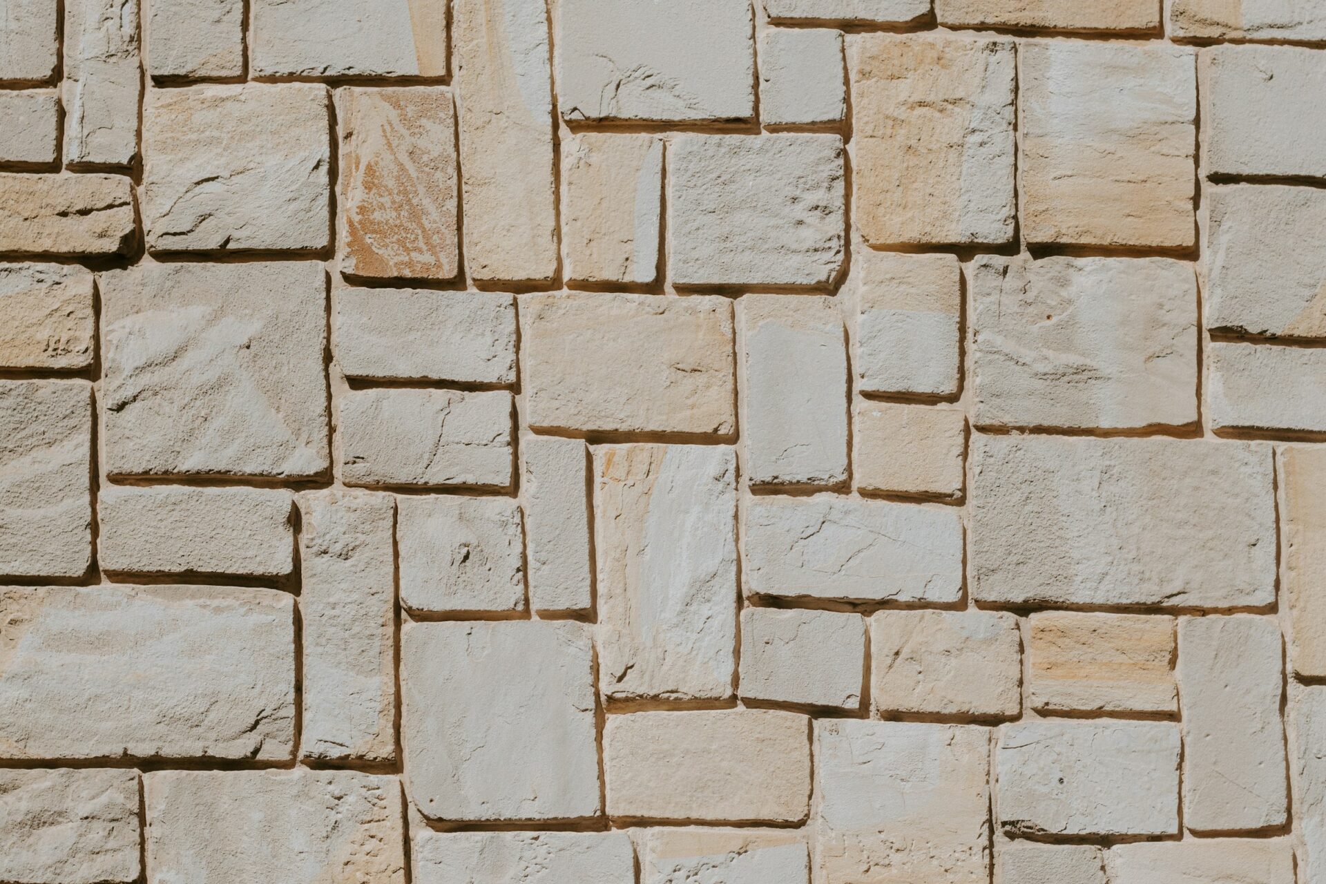 Detail van een gevel van beige natuursteenblokken met fijne voegen